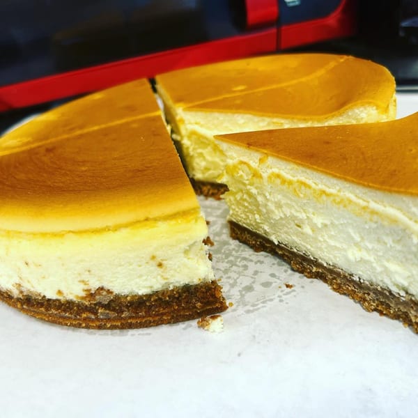 A whole cheesecake with three slices cut out, revealing creamy white filling and a brown crust.
